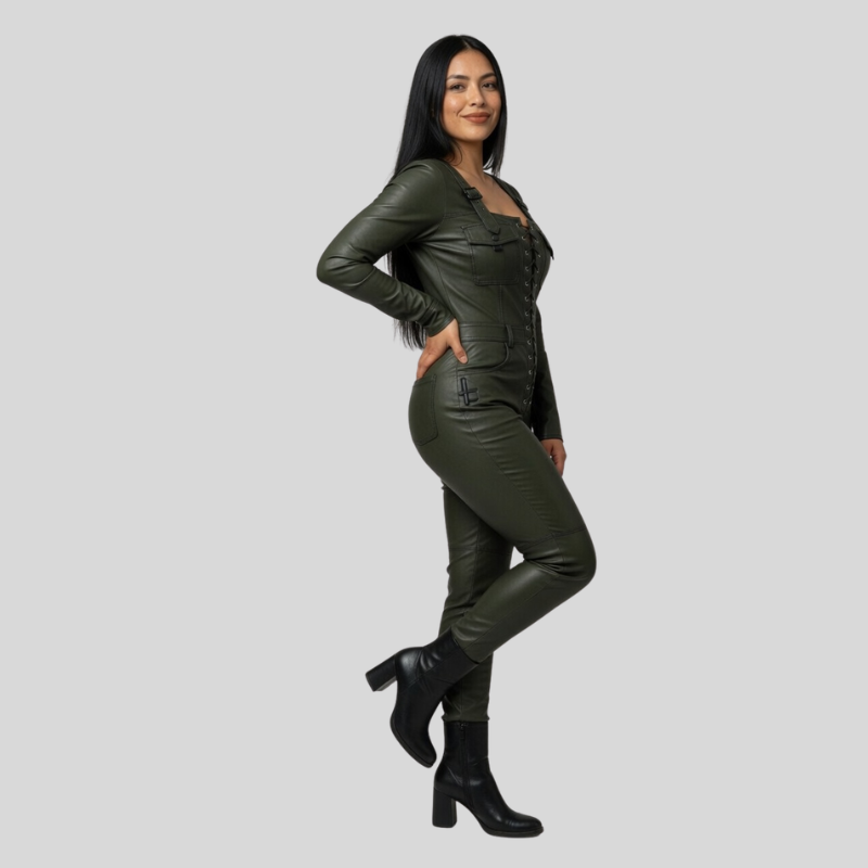 A woman modeling a matching dark olive green leather jumpsuit with black ankle boots, posed against a solid light gray background.